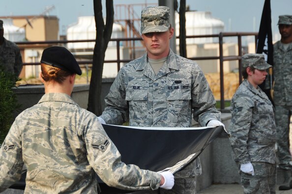 Airman 1st Class Casey Lindsey and Senior Airman Chester Kiluk fold the Prisoner of War/Missing in Action flag during a retreat ceremony at Osan Air Base, Republic of Korea, Sept. 20, 2012. Osan held several events throughout the week to include a 24-hour run and candlelight vigil to remember the more than 83,000 Americans who are missing from World War II, the Korean War, the Cold War, the Vietnam War and the 1991 Gulf War. Lindsey is a 51st Security Forces Squadron defender and Kiluk is a 694th Intelligence Support Squadron critical communications operator. (U.S. Air Force photo/Staff Sgt. Craig Cisek)