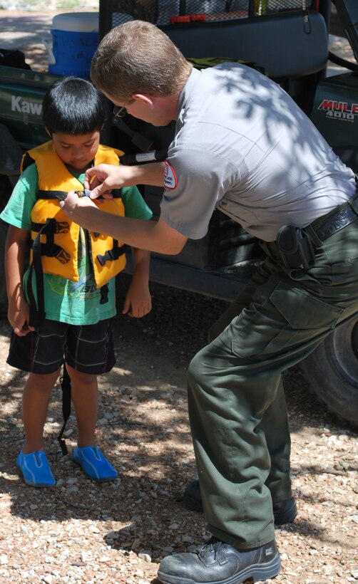 Canyon Lake Natural Resource Specialist Sam Price helps Angel, 5 with a loaner life vest.