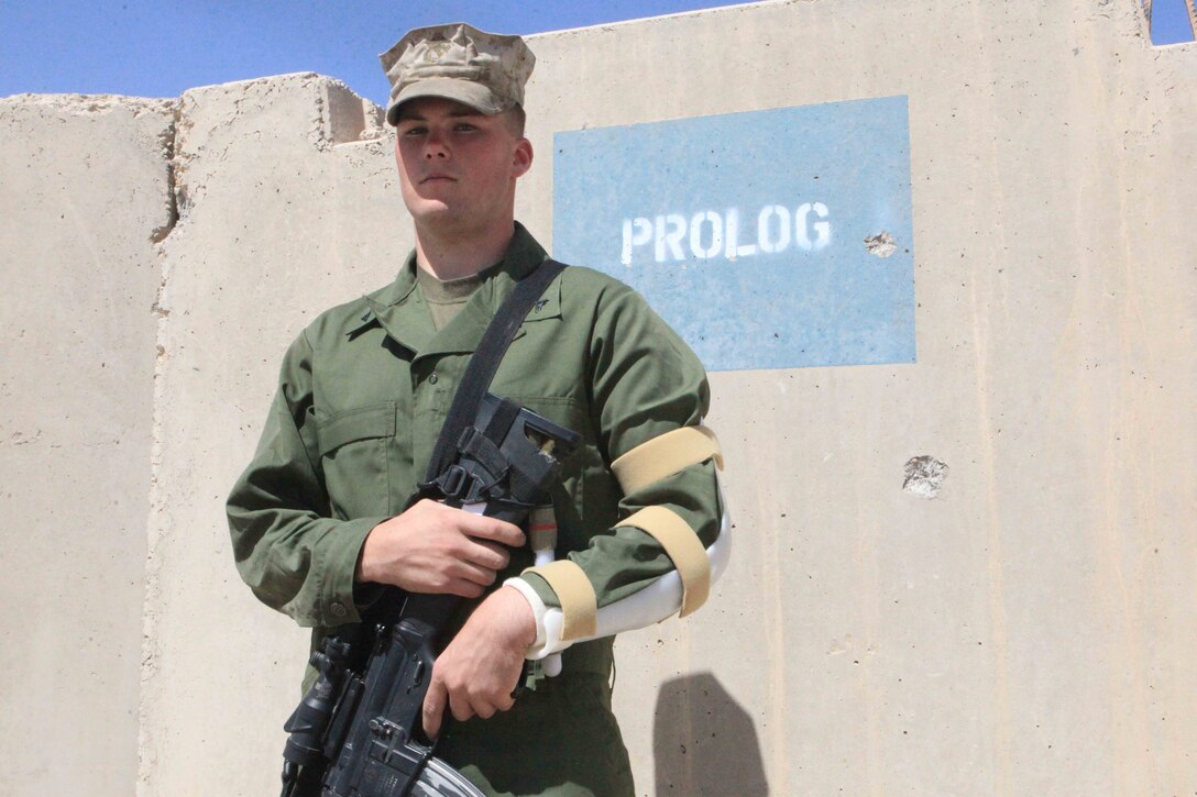 Lance Cpl. Ethan Burk stands in front of a bullet-riddled concrete barrier from the night Camp Bastion was attacked, Sept. 22. Carrying a bullet-scarred rifle and wounded during the attack, Burk and another Marine maneuvered out of the kill zone to inform the British Army?s quick reaction force of the insurgents? fighting position.