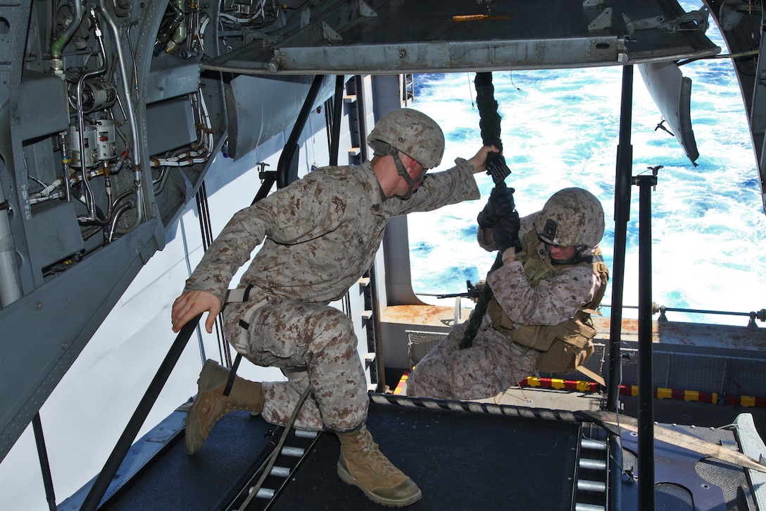 A Marine from the 15th Marine Expeditionary Unit, fast-ropes off the tail of a CH-46E Sea Knight into the hanger bay of the USS Peleliu, Sept. 22.