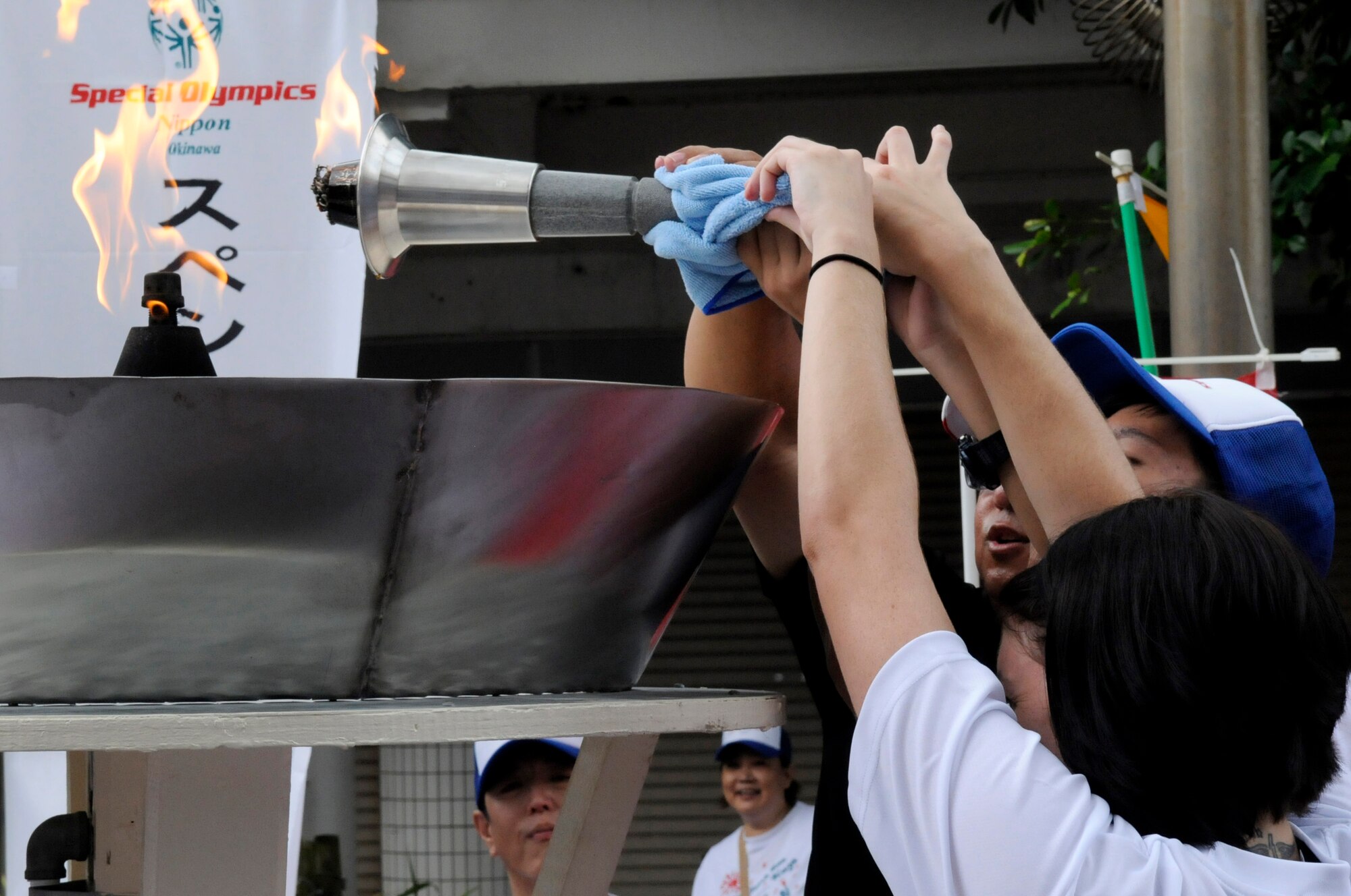 A special needs athlete gets help igniting a giant torch from local volunteers and a Kadena Air Base service member during the 2012 Special Olympics NipponTorch Run, in Okinawa City, Japan, Sept. 22, 2012. More than 100 volunteers from the U.S. military community supported the Nippon Special Olympics event. (U.S. Air Force photo/Airman Tara A. Williamson)