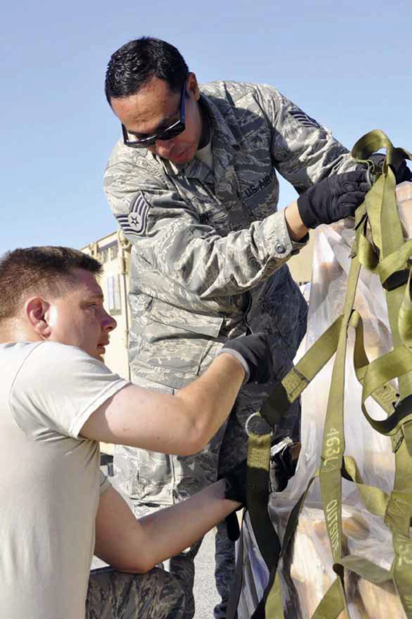Staff Sgt. David Marin and Tech. Sgt. Steven Holland, 50th Aerial Port Squadron cargo processors, secure cargo netting to a pallet in the Joint Inspection staging area at March Air Reserve Base, Calif., Sept. 18, 2012, as part of an Operational Readiness Exercise. (U.S. Air Force photos by Master Sgt. Linda Welz)