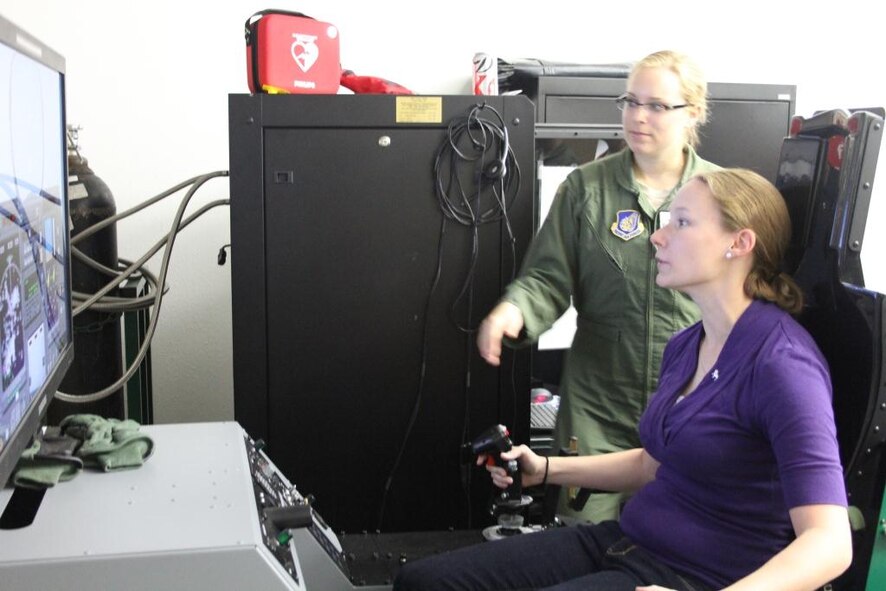Michelle Stocker, wife of F-22 pilot Capt. Rich Stocker, tests her skills on a flight simulator. The spouses of active duty and Reserve F-22 pilots from the 525th and 302nd Fighter Squadrons received an up close look at the F-22 mission during the Spouses Blue Carpet day here Sept. 21. The tour consisted of a commanders briefing, and tours of the Air Traffic Control Tower, Egress Trainer and Hush House. (Courtesy Photo) 