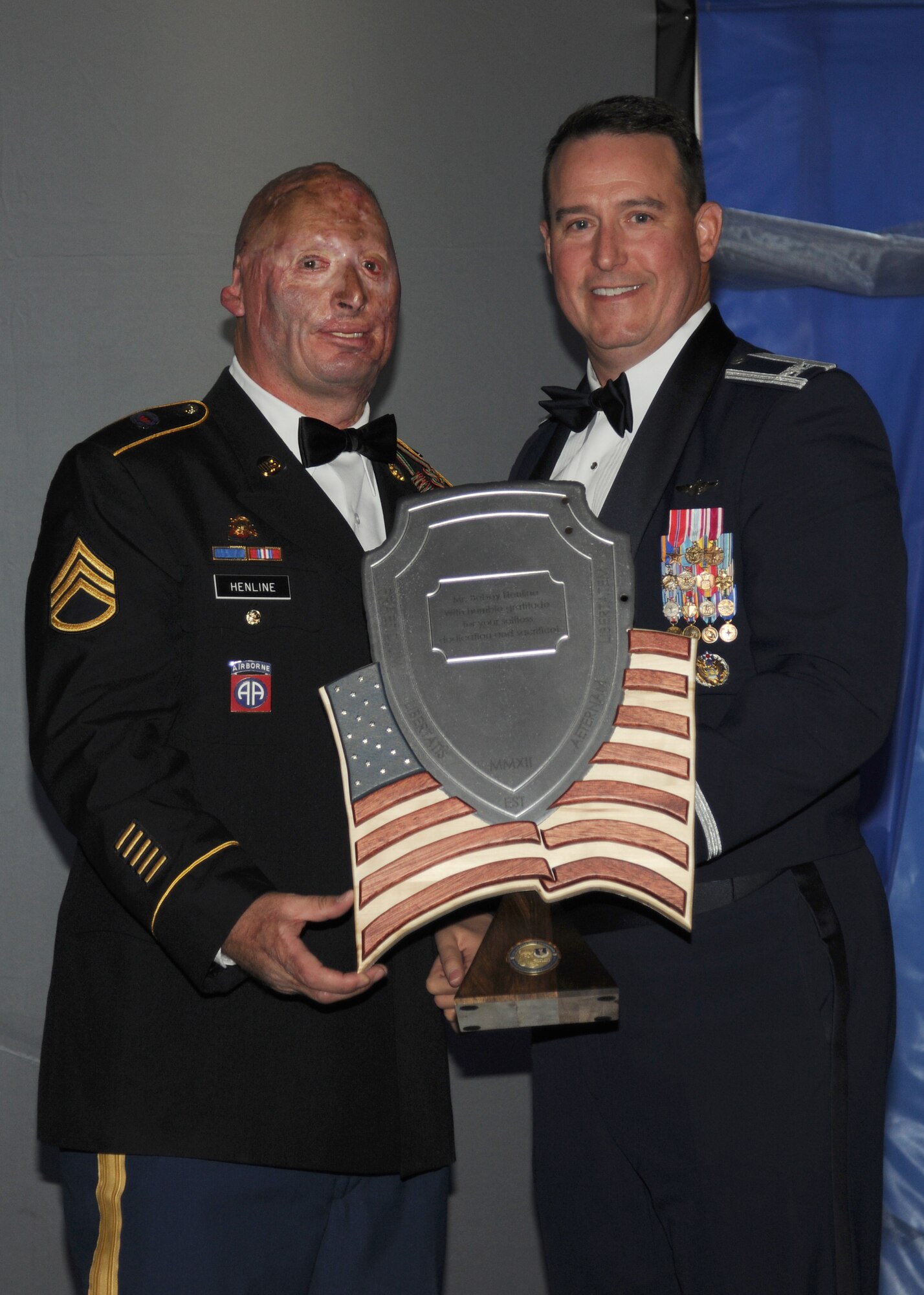 Col. Tim Bush, 319th Air Base Wing commander, presents a commemorative plaque to keynote speaker Bobby Henline at the Air Force Ball, Sept. 21, 2012, on Grand Forks Air Force Base, N. D. Mr. Henline is an Army veteran who survived a roadside bomb attack in 2007 and now performs motivational speaking through stand-up comedy. (U.S. Air Force photo/Airman 1st Class Ashley N. Taylor) 