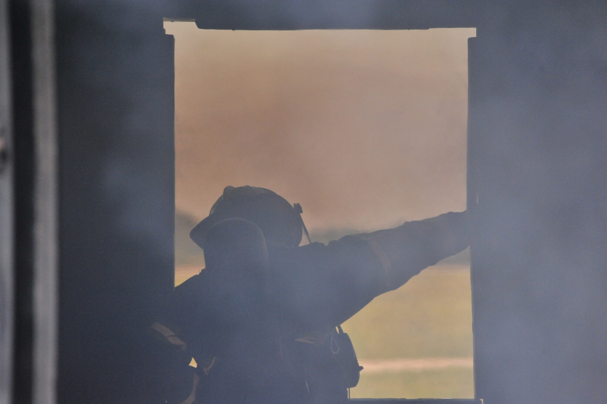 A member of the Maxwell Air Force Base Fire Department looks outside from within a burning structure during an exercise here, Sept. 20. Firefighters use these simulations to maintain their certifications. (U.S. Air Force photo by Airman 1st Class William Blankenship) 