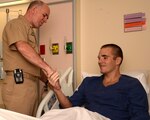 Vice Adm. Matthew L. Nathan, surgeon general of the Navy, visits with Andrew Knudson and presents him with a coin. Knudson was training in Navy dentistry when he became ill and plans to complete his training after he recovers. Nathan visited with wounded Marines, Sailors, and the staff of Naval Health Clinic Corpus  Christi Detachment at the San Antonio Military Medical Center Sept. 13 prior to visiting and encouraging Knudson. (Photo by L.A. Shively, JBSA-Fort Sam Houston Public Affairs)