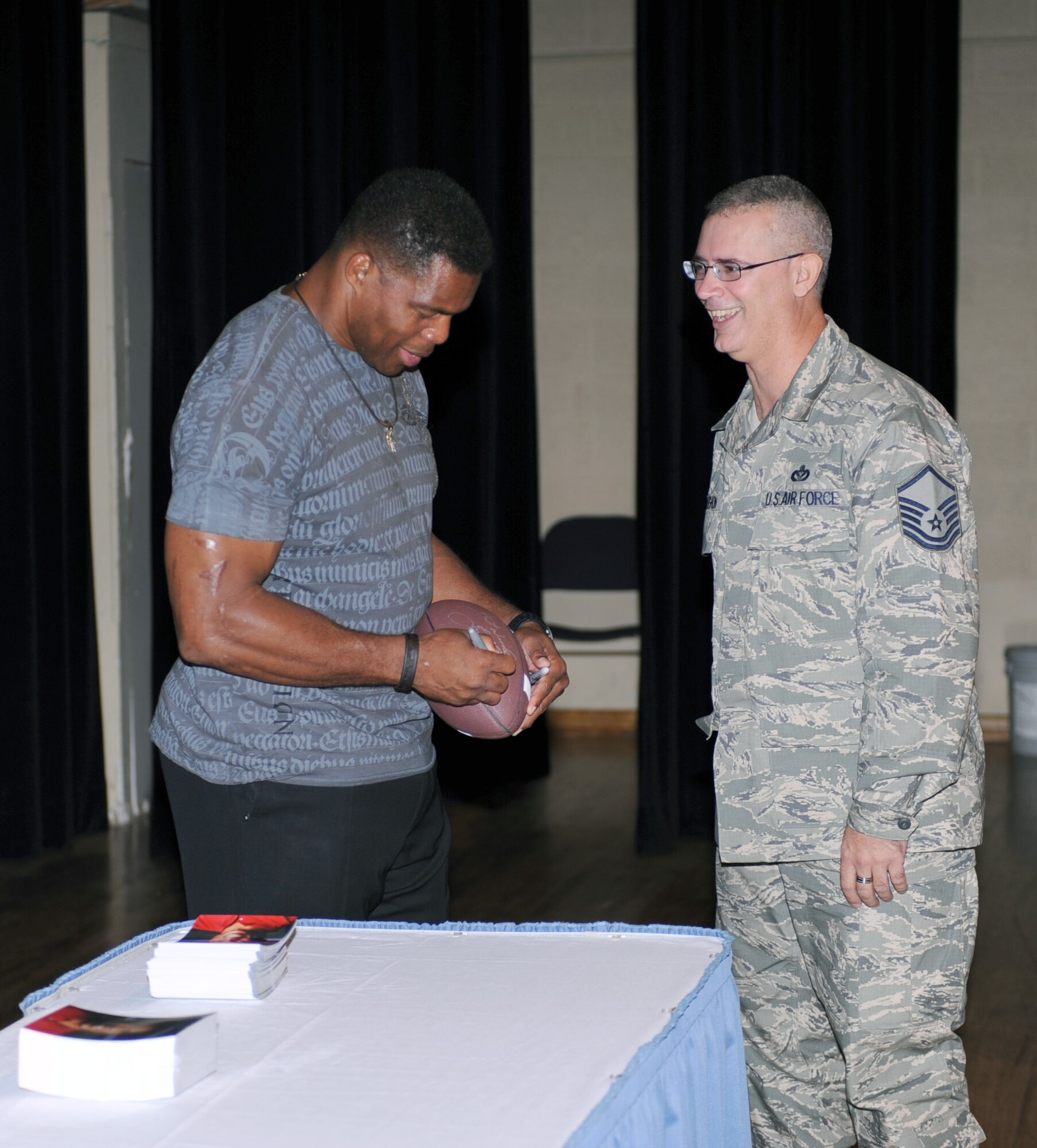 Herschel Walker signs a football for an excited Airman after speaking about his past experiences at the base theater on Davis-Monthan Air Force Base, Ariz., Sept. 21. (U.S. Air Force photo by Airman 1st Class Michael Washburn/Released)