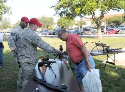 Tech. Sgt. Mark Fox (left), and Staff Sgt. Joshua Clements (center), 902nd Security Forces Squadron combat arms instructors, explain modern weaponry to Larry Wagner during the retiree appreciation event held at Joint Base San Antonio-Randolph, Texas, Sept. 22. The event is held annually at the Kendrick Club to educate the local retiree community on services available to them. (U.S. Air Force photo by Rich McFadden) 