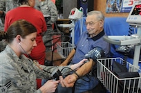 Senior Airman Kelly Boos (left), 359th Medical Operations Squadron medical technician, takes a blood pressure reading for Bill Jurczyn during the retiree appreciation event held at Joint Base San Antonio-Randolph, Texas, Sept. 22. The event is held annually at the Kendrick Club to educate the local retiree community on services available to them. (U.S. Air Force photo by Rich McFadden) 