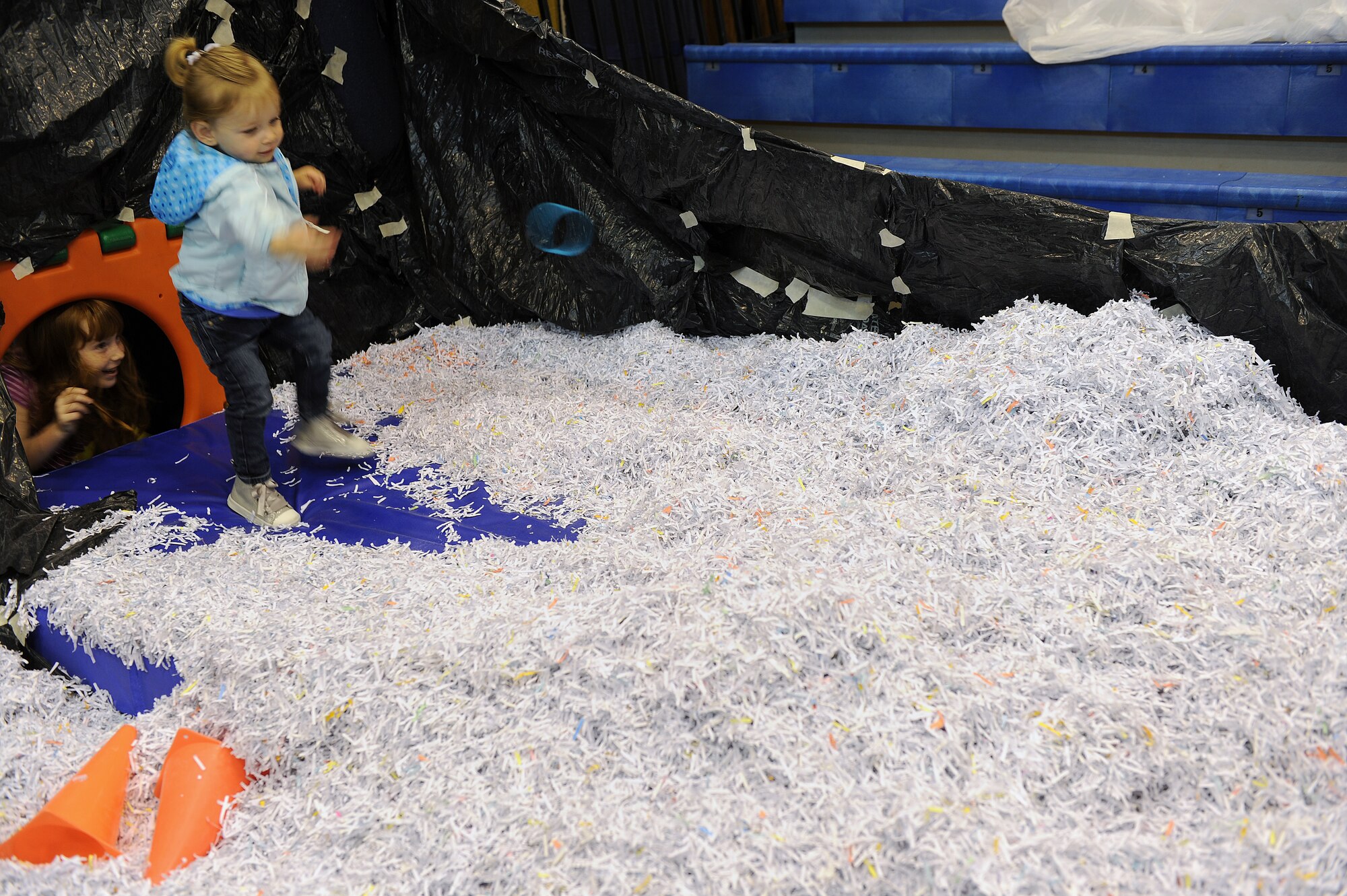 RAF MILDENHALL, England -- From right, Emma Sluder chases after a blue ring in the shredded paper pit while Abby Hardin looks on during the World Wide Day of Play hosted at the RAF Mildenhall Youth Center Sept. 22, 2012. More than 900 people attended the Worldwide Day of Play which featured games, bouncy castles, Pets as Therapy dogs, go-karts and more. (U.S. Air Force photo/Tech. Sgt. Stacia Zachary)