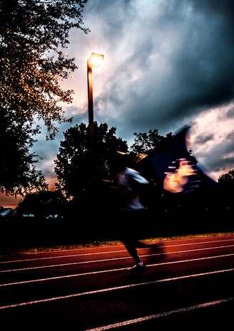An Airman from Joint Base Charleston carries the Prisoner of War/Missing in Action flag around a track just at sunset during the POW/MIA Run Sept. 20. Different units from the joint base carried the flag for 30 minutes each from 3:30 p.m. Sept. 20 to 3:30 p.m. Sept. 21 in honor of all POWs and MIAs. (U.S. Air Force photo/Senior Airman Dennis Sloan)
