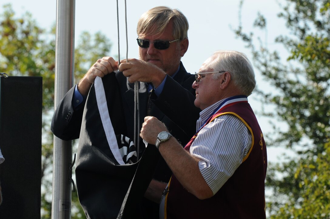 Matthew Hartman, left, 358 Air Force Sergeant Association chapter president, and retired U.S. Navy Commander George Coker, former North Vietnam prisoner of war, attach the POW-MIA flag to the halyard during a remembrance ceremony at Langley Air Force Base, Va., Sept. 21, 2012. This type of flag, a silhouette of a man’s head with barbed wire and a watchtower in the background, has flown over the White House on National POW-MIA Recognition Day since 1982. (U.S. Air Force photo by Senior Airman Racheal Watson/Released)