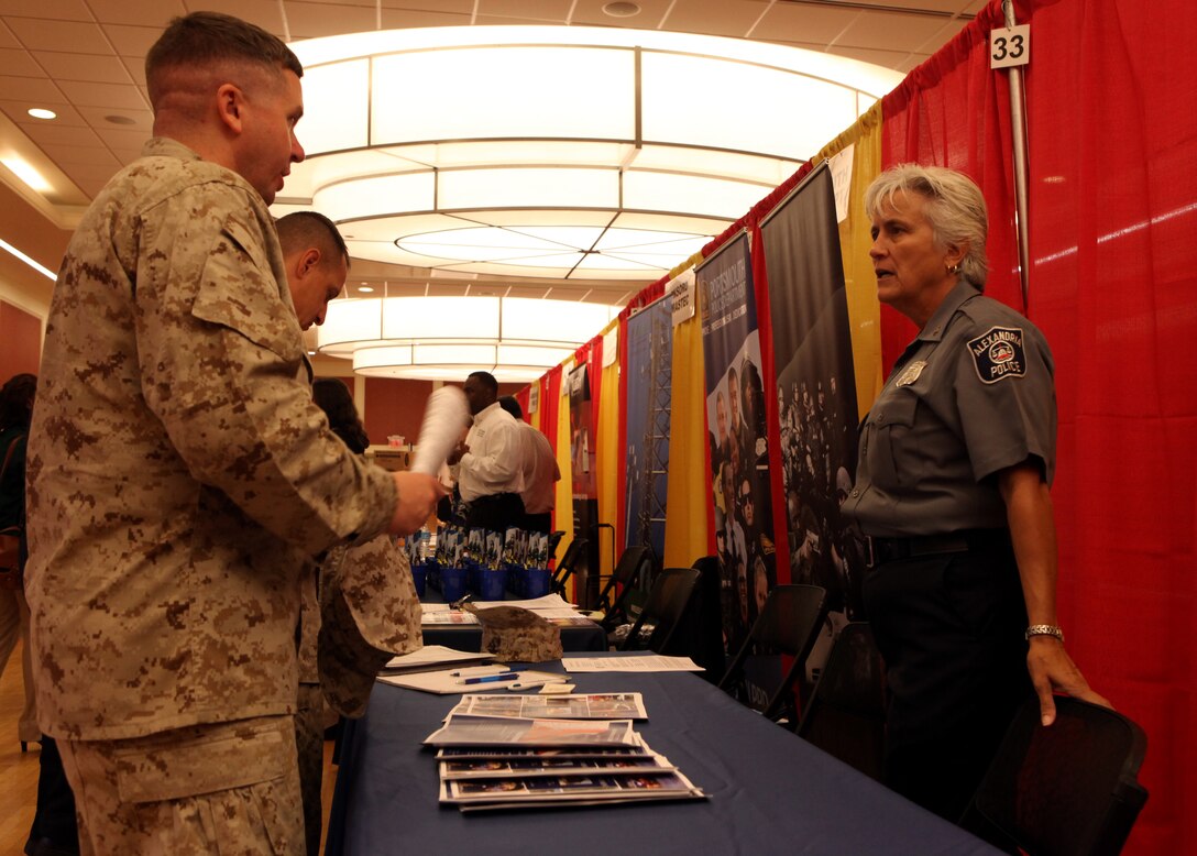 An Alexandria, Va. Police Department representative describes the benefits of working for their police force to two Marines aboard Marine Corps Base Camp Lejeune during the bi-annual Job Fair and Education Exposition Sept. 19. Many different employers were present at the event, with police departments being the most prevalent.