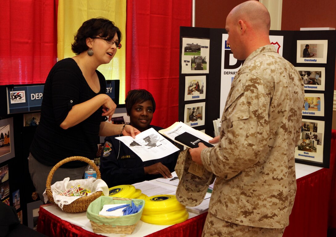 Two Department of Public Safety career representatives give a hand-out to a Marine attending the Job Fair and Career Exposition aboard Marine Corps Base Camp Lejeune Sept. 19. Many Marines were hoping to find a job they would feel comfortable working after leaving the Marine Corps.