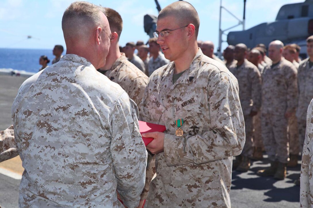 Corporal Derrick M. Sikes, radio operator, Command Element, 15th Marine Expeditionary Unit, is presented the Navy Marine Corps Achievement Medal during an award ceremony on the flight deck of the USS Peleliu, Sept 23.  The MEU is currently embarked about the Peleliu Amphibious Ready Group for a Western Pacific deployment.   Sikes, 22, is from Nashville, Tenn.