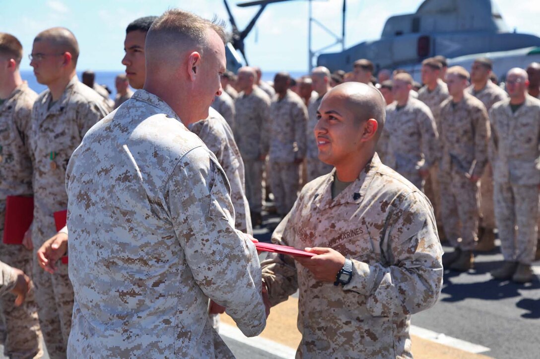 Sergeant Sigilfredo Garcia, armory chief, Command Element, 15th Marine Expeditionary Unit, is presented a Certificate of Commendation during an award ceremony on the flight deck of the USS Peleliu, Sept 23.  The MEU is currently embarked about the Peleliu Amphibious Ready Group for a Western Pacific deployment.   Garcia, 26, is from Lexington, Neb.