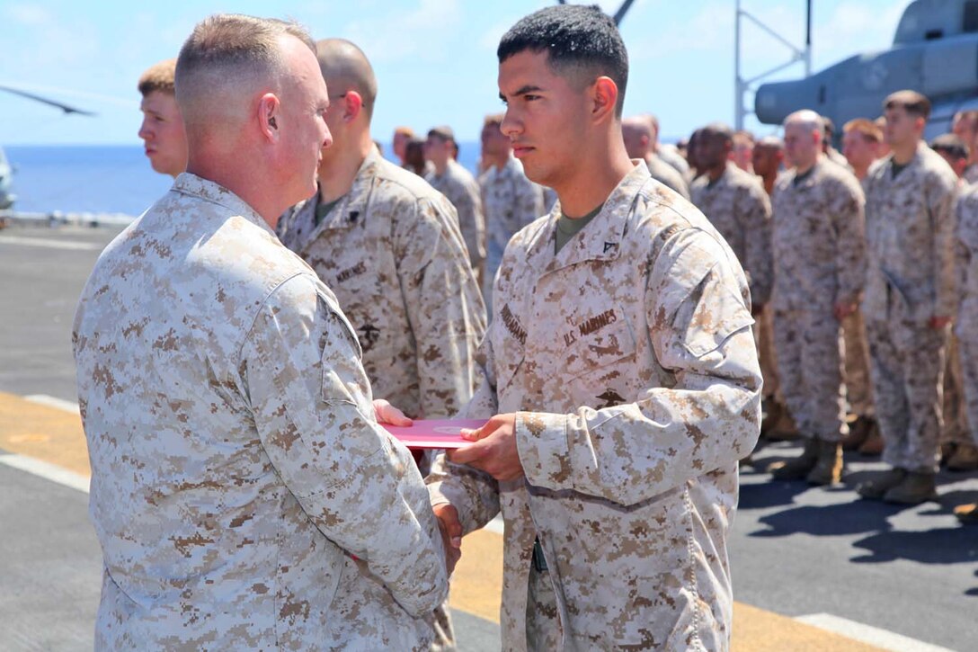 Lance Cpl. Brendon C. Burke-Adams, data systems technician, Command Element, 15th Marine Expeditionary Unit, is presented a Certificate of Commendation during an award ceremony on the flight deck of the USS Peleliu, Sept 23. The MEU is currently embarked about the Peleliu Amphibious Ready Group for a Western Pacific deployment.  Burke-Adams 19, is from Banning, Calif.   