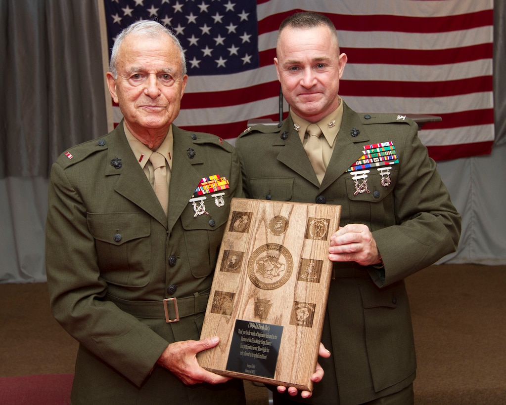 Retired Chief Warrant Officer 4 Ed Farah and Col. J. J. Dill, the commanding officer of the 1st Marine Corps District, show off the plaque presented to Farah at the conclusion of the 1 MCD’s Mess Night Sept. 7.  Farah was the guest of honor at the mess night and served in the Marine Corps from 1942 to 1983.  He was present at the Japanese surrender during World War II and also served in the Korean War.