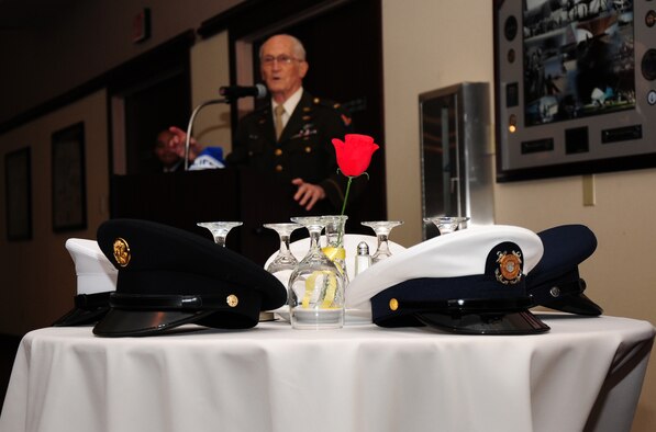 Service caps from all branches of the military rest on the POW/MIA table as Leonard Kovar speaks about being a POW in WWII during a Recognition Day Breakfast at the Recce Point Club, Beale Air Force Base, Calif., Sept. 21, 2012. The event was organized by Air Force Sergeants Association Chapter 1372. (U.S. Air Force photo by Senior Airman Allen Pollard/Released)