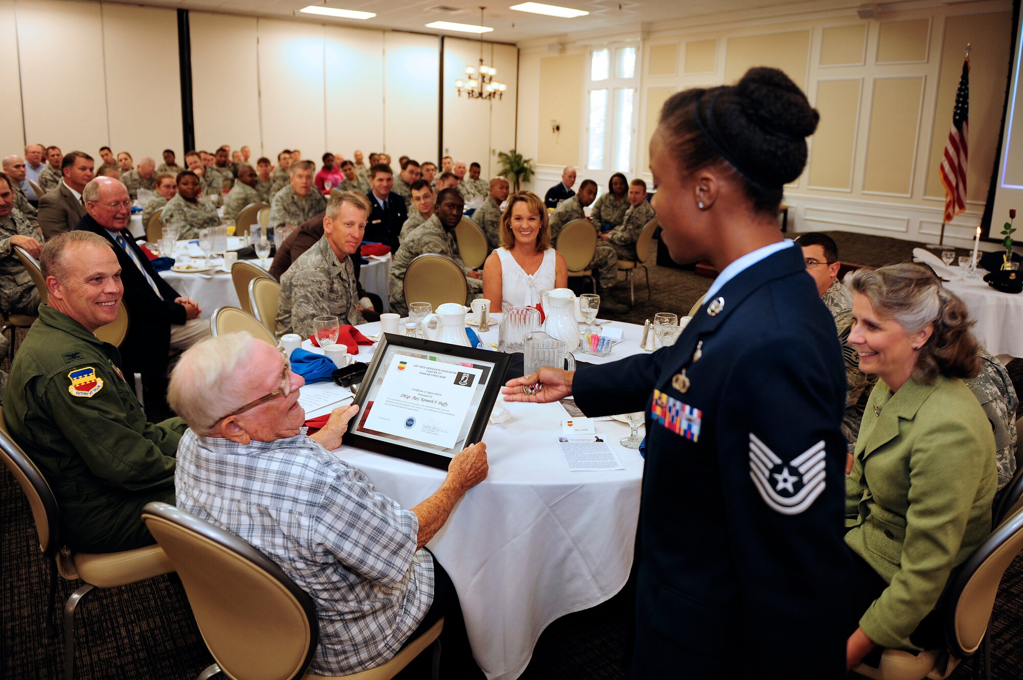 Tech. Sgt. Thyiatira Singleton, 20th Force Support Squadron Airman Leadership School instructor and vice president of the Air Force Sergeants Association chapter 377, presents guest speaker retired Senior Master Sgt. Kenneth Duffy with a coin as a small token of gratitude for sharing his story at the prisoner of war and missing in action breakfast, Shaw Air Force Base, S.C., Sept. 20, 2012. Duffy spent a year as a prisoner of war in camp Stalag 17-B in Krems, Austria during World War II, and shared that experience during the ceremony. (U.S. Air Force photo by Airman 1st Class Daniel Blackwell/Released)