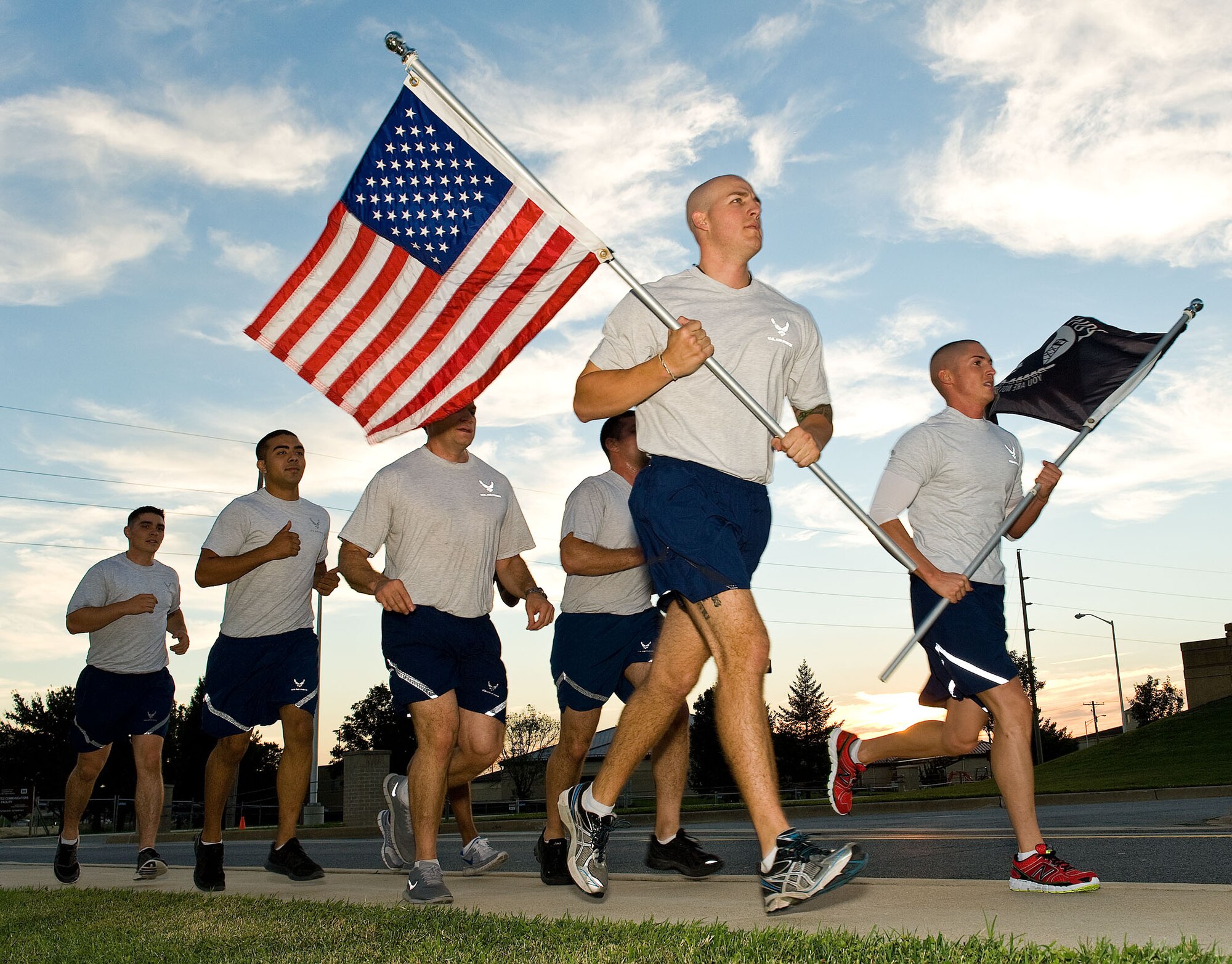 Airmen run with American and Prisoner of War/Missing in Action flags in hand during POW/MIA Remembrance Day Sept. 20, 2012, at Dover Air Force Base, Del. More than 200 Team Dover members participated in the run, which amounted to more than 200 laps around buildings 200, 201, 202, 204 and 205. (U.S. Air Force photo by Roland Balik)