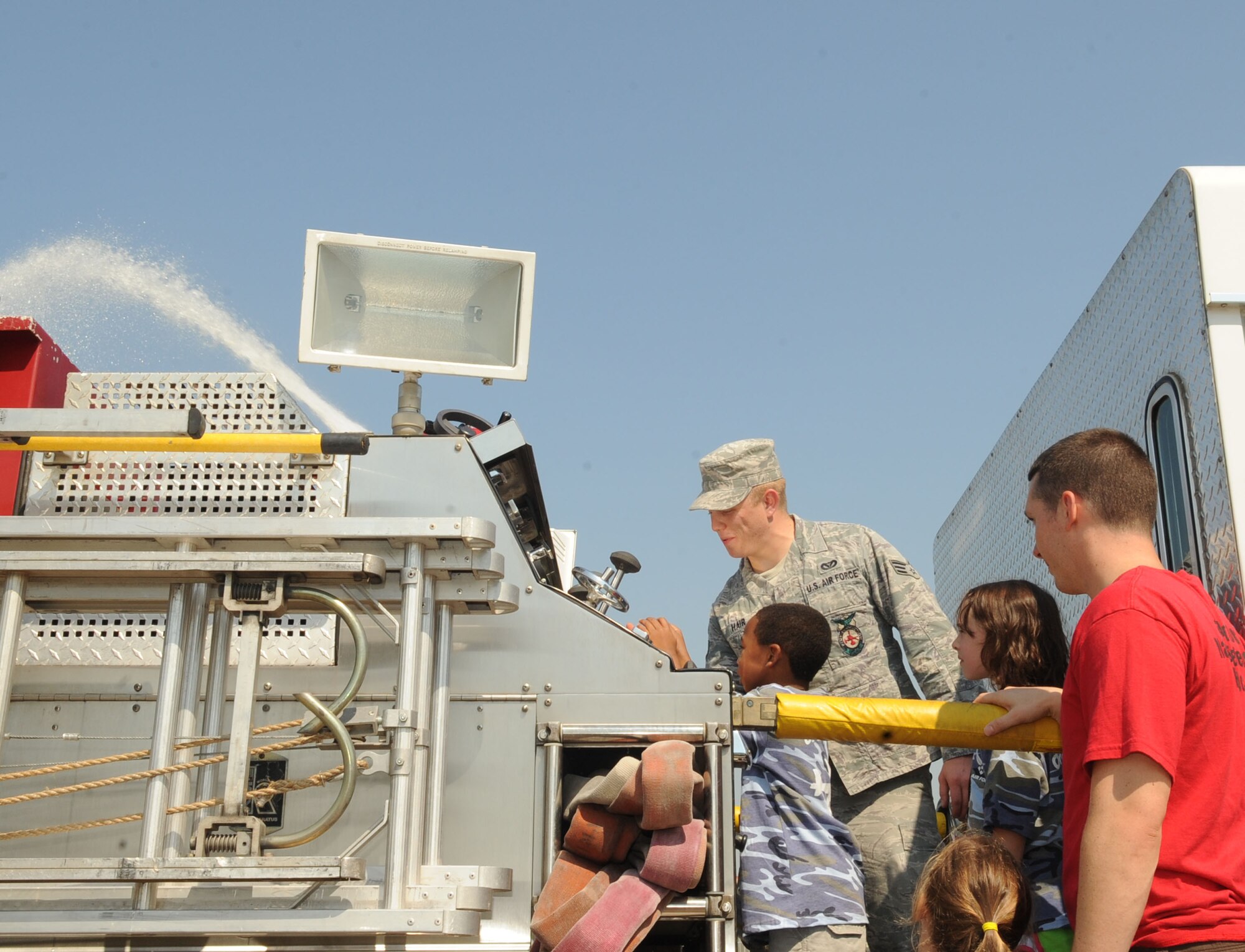 Senior Airman Kasey Hair, 2nd Civil Engineer Squadron, shows children how to operate a deck gun on a fire truck during Operation Hero on Barksdale Air Force Base, La., Sept 22. Children were also briefed on fire safety and were given the opportunity to use a real fire hose. (U.S. Air Force photo/Senior Airman Kristin High)(RELEASED)
