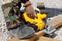 U.S. Air Force Airman Demetri Tsika, 4th Civil Engineer Squadron structural apprentice, cuts a piece of wood during Phase II of Operational Readiness Exercise Coronet Warrior 12-04 at a simulated deployed location on Seymour Johnson Air Force Base, N.C., Sept. 20, 2012. Construction of new equipment to be used in tent city aids the overall readiness for those participating in the Operation Readiness Exercise. (U.S. Air Force photo/Airman 1st Class John Nieves Camacho/Released)