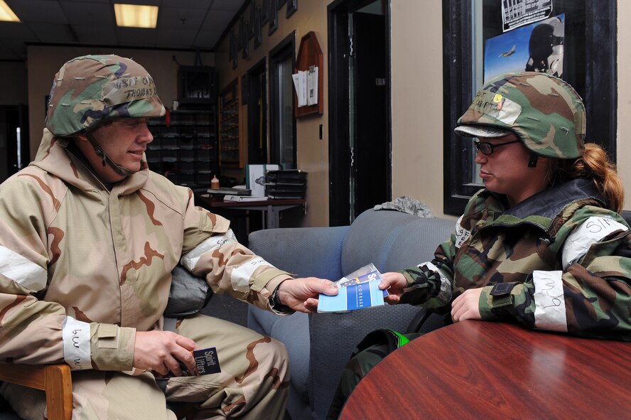 U.S. Air Force Chap. (Capt.) Thomas Baize, 4th Operations Group chaplain, hands Staff Sgt. Rachel Roberts, 335th Aircraft Maintenance Squadron weapons team chief, guidebooks for spiritual outreach during Phase II of Operational Readiness Exercise Coronet Warrior 12-04 at a simulated deployed location on Seymour Johnson Air Force Base, N.C., Sept. 20, 2012. The guidebooks offer reading tips on self improvement such as confidence, strength and modesty. (U.S. Air Force photo/Airman 1st Class John Nieves Camacho/Released)