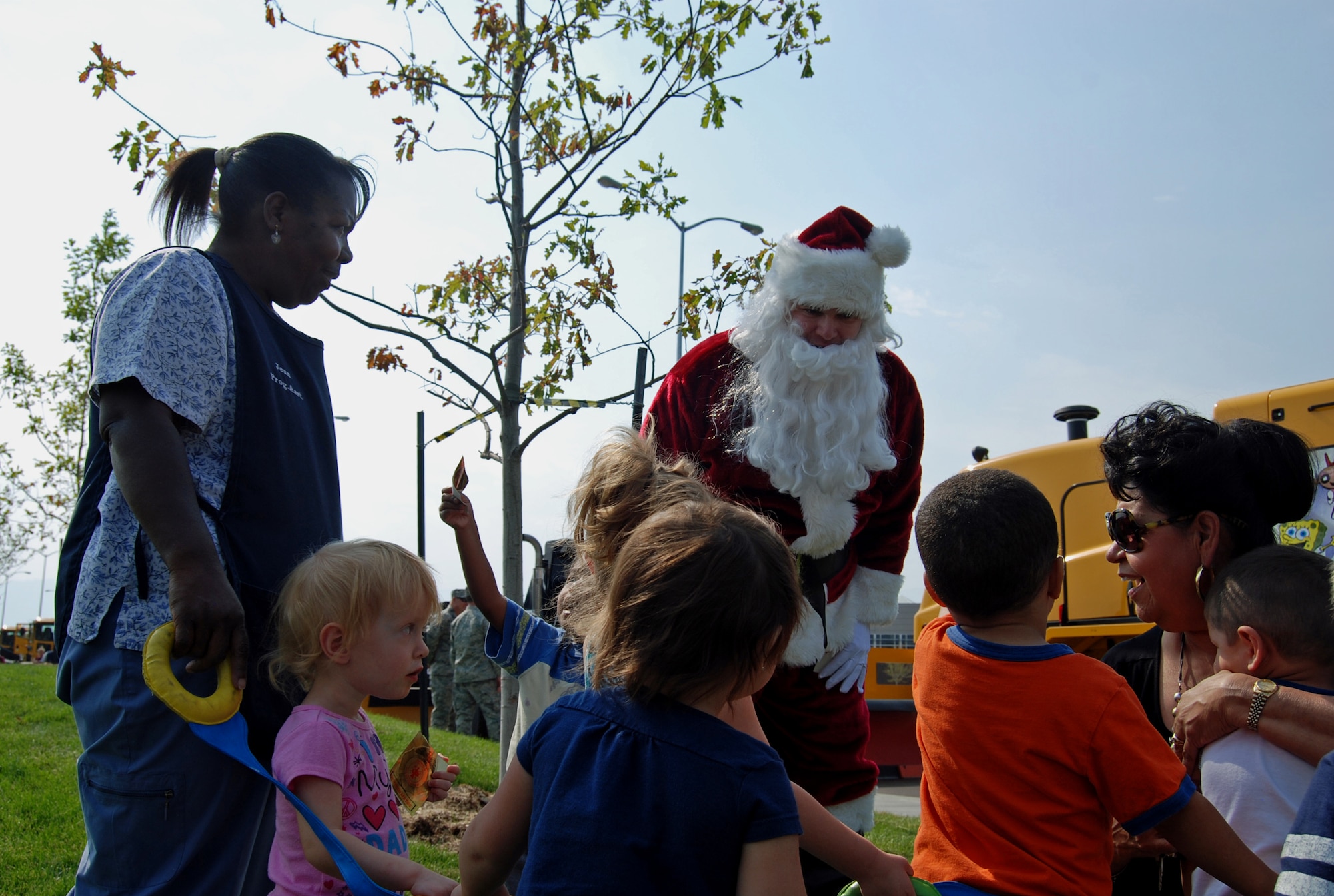 Santa hands out stickers to children outside the main Child Development Center during the annual Snow Parade Sept. 19, 2012. In addition to meeting Santa, kids got to get inside fire trucks, snow plows, and dump trucks. The purpose of the Snow Parade is not only to educate children and the base populace, but also to ensure that all the equipment is in proper working order before the winter season. (U.S. Air Force photo/Lea Johnson)