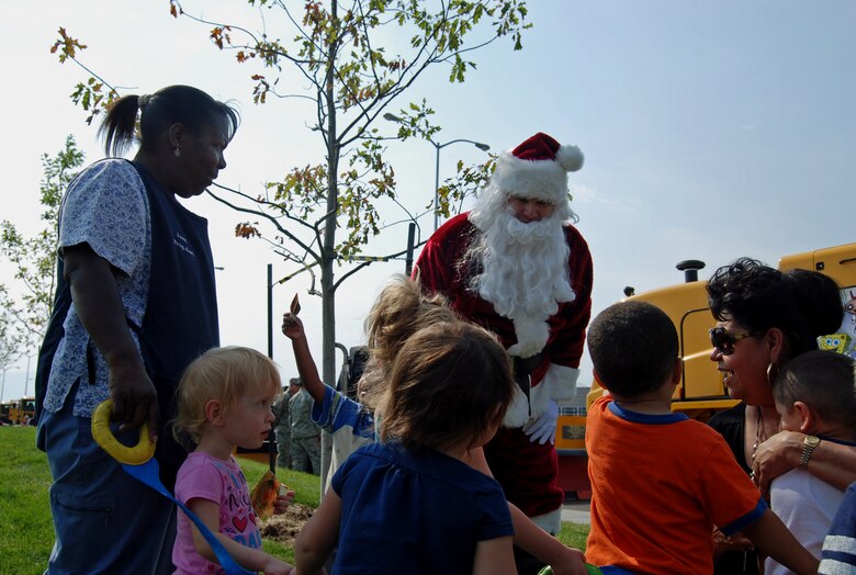 Santa hands out stickers to children outside the main Child Development Center during the annual Snow Parade Sept. 19, 2012. In addition to meeting Santa, kids got to get inside fire trucks, snow plows, and dump trucks. The purpose of the Snow Parade is not only to educate children and the base populace, but also to ensure that all the equipment is in proper working order before the winter season. (U.S. Air Force photo/Lea Johnson)