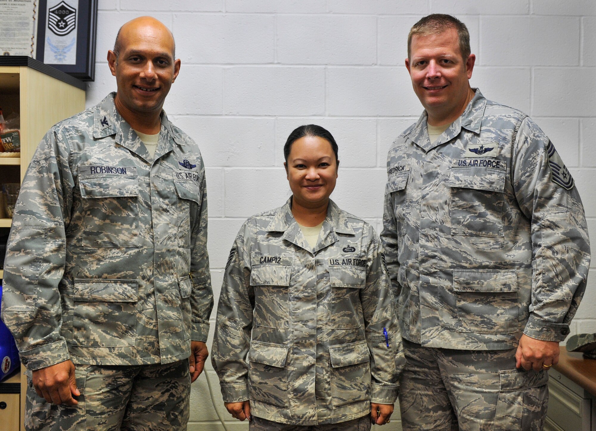 Col. Brian Robinson, 19th Airlift Wing commander and Chief Master Sgt. Sam Fredrick, 61st Airlift Squadron superintendent, pose for a photo after they congratulate Tech. Sgt. Carol Campiz, a 19th Maintenance Operations Squadron maintenance training flight scheduler, for her selection as the Combat Airlifter of the week Sept. 19, 2012, at Little Rock Air Force Base, Ark. Campiz, a Jacksonville, Fla., native, was praised by Lockheed Martin Training Solutions for her professional attitude and zero errors. (U.S. Air Force photo by Airman 1st Class Rusty Frank)