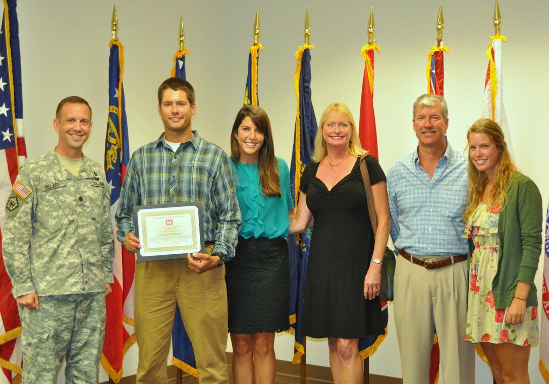 Lt. Col. James A. DeLapp, Nashville District commander, honors Curtis Ferguson, civilian, with a certificate of appreciation and a gold commander’s medallion at the Estes Kefauver Federal Building Sept. 17, 2012.  Ferguson heroically pulled two people from the hazardous waters directly downstream of Center Hill Dam after their boat swamped and capsized by the strong current generated by the sluice gates Aug. 16, 2012.  Ferguson was joined (left to right) by his wife Meagan Ferguson, Tricia Ferguson, mother, Scott Ferguson, father, and Casey Ferguson, sister. (USACE photo by Amy Redmond)