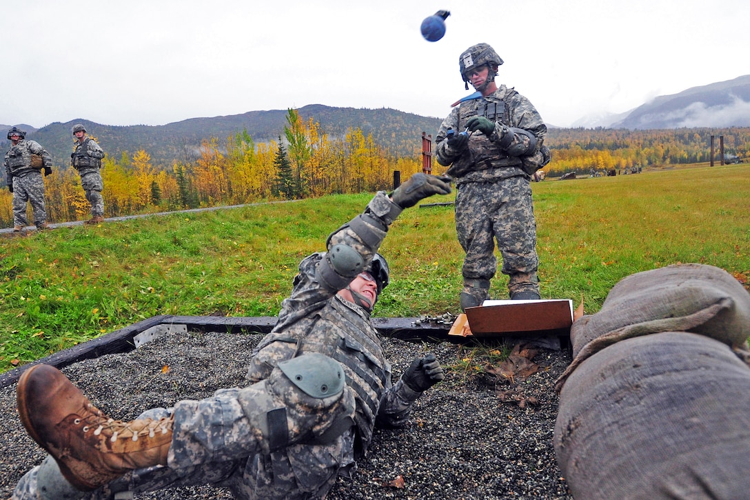 Army Pfc. Marcus Figueroa, lying down, throws a practice hand grenade as Army Spc. Michael Gaffney seats a new fuse in another practice hand grenade for the next soldier on Joint Base Elmendorf-Richardson, Alaska, Sept. 20, 2012. Figueroa and Gaffney are assigned to 545th Military Police Company.