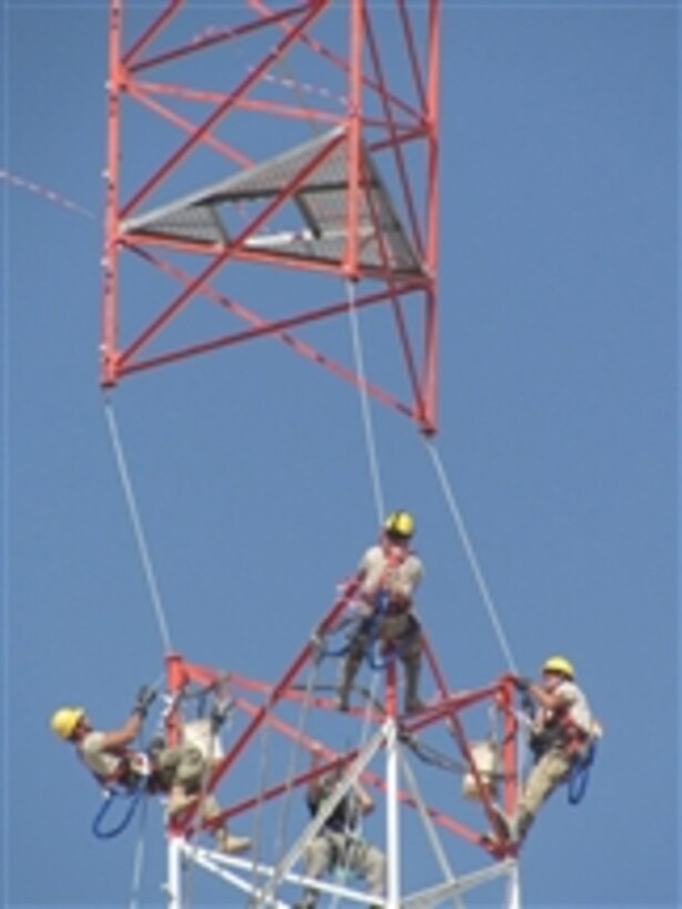 Members of the 455th Expeditionary Communications Squadron prepare to connect two tower sections as a helicopter lowers the top section into place at Bagram Airfield, Afghanistan, on Sept. 3, 2012.  Several Air National Guard engineering installation squadrons have deployed to Bagram to combine their efforts to build and setup the 170-foot communications tower. 