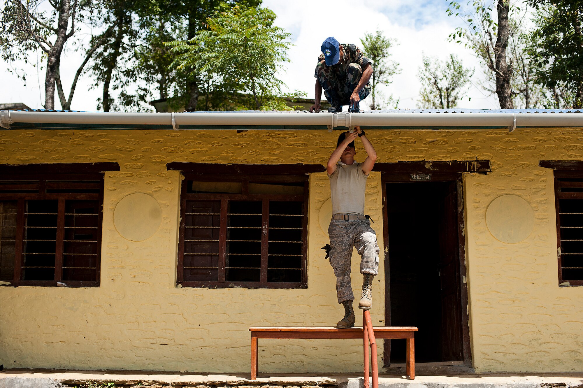 Airman 1st Class Thomas Zajac, 354th Civil Engineer Squadron, Eielson Air Force Base, Alaska, installs a new gutter with a Nepalese army soldier during U.S. Pacific Command's Operation Pacific Angel 12-4 in Nepal. Nepal army and U.S. Pacific Air Forces’ engineer team renovated and constructed buildings of the Machhapuchhre Higher Secondary School and health post of Dhikur Pokhari Village Development Committee. Pacific Angel is a Pacific Air Forces planned event that enhances humanitarian assistance and disaster relief capabilities between the United States and Pacific partners. The U.S. was invited by the Nepal government to provide support by conducting medical, optometry and civil engineering programs. Operations like Pacific Angel build and sustain relationships with multinational partners in the Asia-Pacific region. (U.S. Air Force photo/Master Sgt. Jeffrey Allen)
