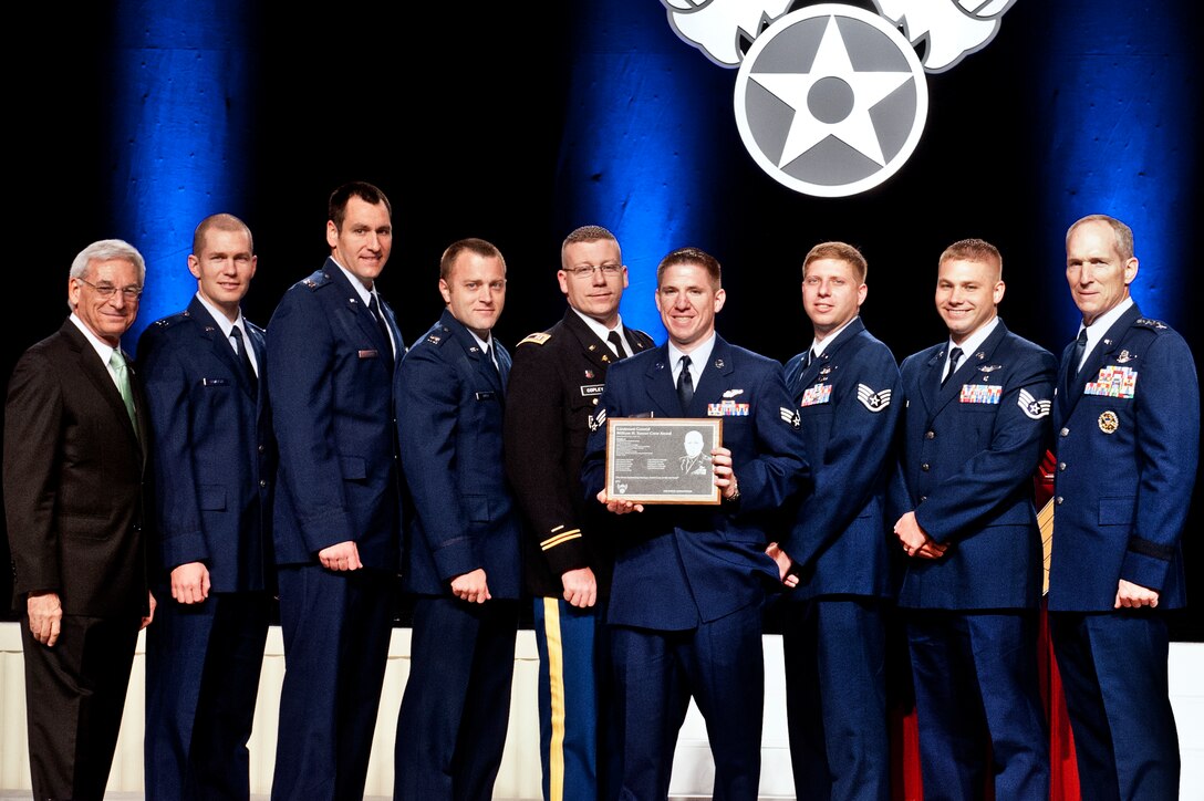 The aircrew of FEVER 11 is presented the Lt. Gen. William H. Tunner Award by Sandy Schlit, Chairman of the board for the Air Force Association (far left), and Gen. Mike Hostage, commander of Air Combat Command (far right), at the Annual Air and Space Conference and Technology Exposition award ceremony, Sept. 17, 2012 in Washington D.C. FEVER 11 was named the most outstanding airlift crew in the U.S. Air Force. The crew won the award for a casualty evacuation mission they performed Dec. 24, 2011, while deployed to Afghanistan. (U.S. Air Force photo by Staff Sgt. Joshua J. Garcia/Released) 
