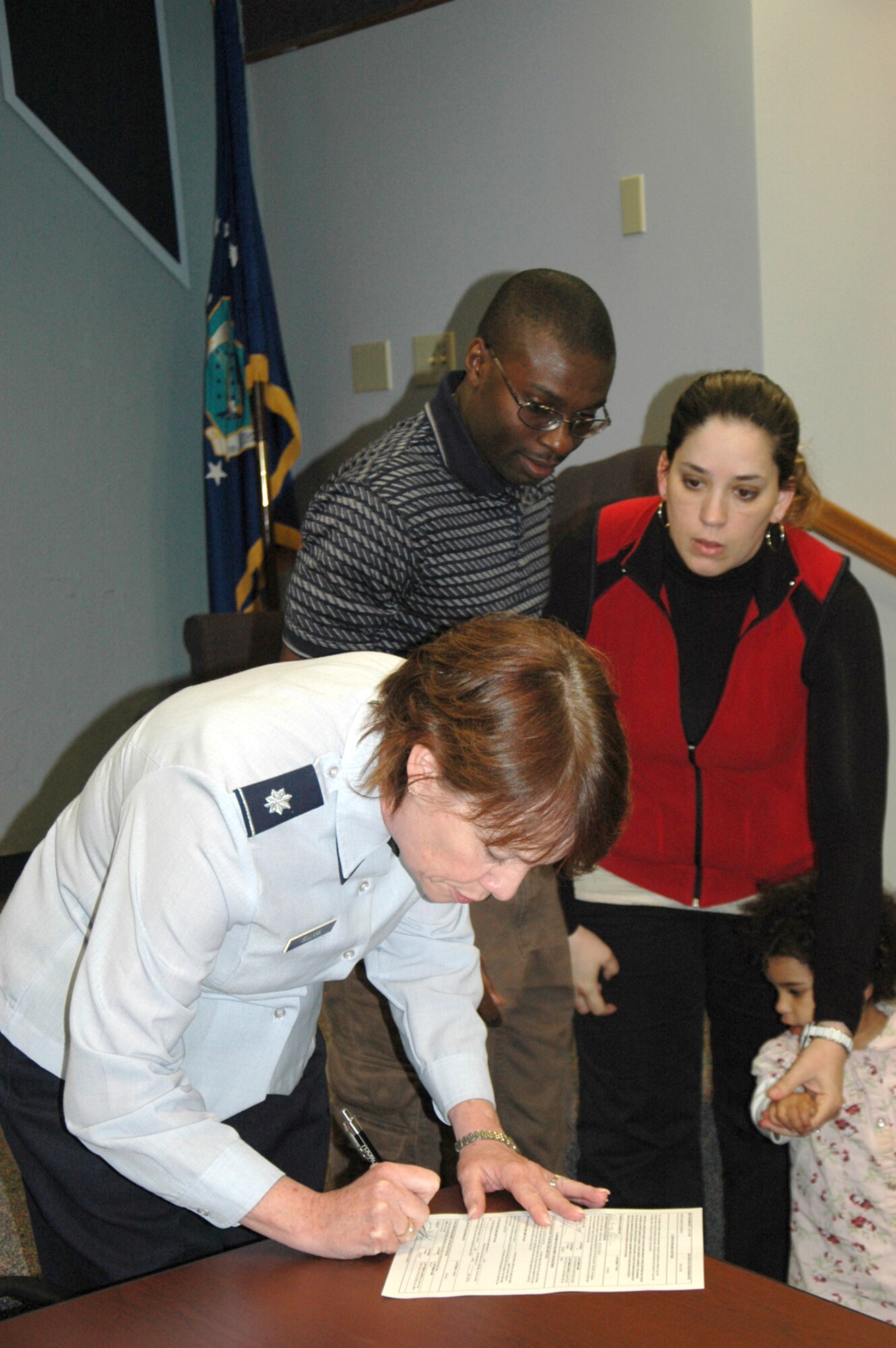 Adedapo Odupitan, center, watches as Lt. Col. Anna Sullivan, 446th Airlift Wing, signs his enlistment papers after he was sworn in to the Air Force Reserve Sept. 13 at McChord Field, Wash.  Odupitan, supported by his wife Heidi, became the 90th recruit for Master Sgt. Christopher Brown. (U.S. Air Force photo by Sandra Pishner)