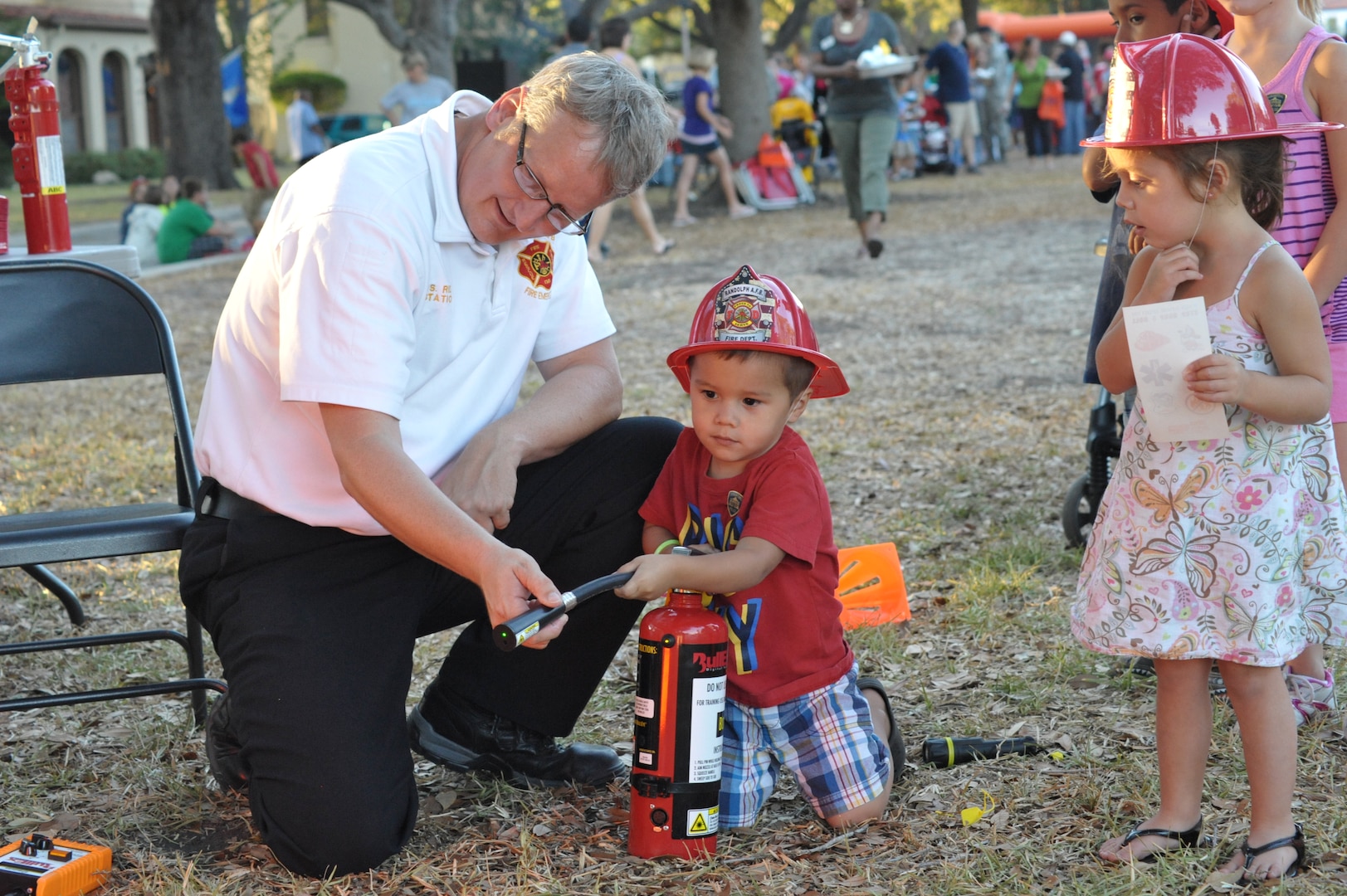 Scott Ridenour, 902nd Civil Engineer Squadron, teaches Fernando Leal how to use a fire extinguisher during the 2011 National Night Out event at Joint Base San Antonio-Randolph. This year's event is scheduled for Oct. 2. (U.S. Air Force photo by Airman 1st Class Alexis Siekert)