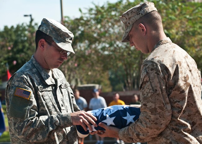 Army Sergeant Daniel Mollet and Marine Corporal Kyle Bazner from the Naval Consolidated Brig Charleston, fold the American flag at the Prisoner of War/Missing in Action Retreat ceremony Sept. 21, 2012, at Joint Base Charleston – Air Base, S.C. The ceremony was held in honor of all POWs and military members who never returned home from action or paid the ultimate sacrifice for American freedom. (U.S. Air Force photo / Staff Sgt. Katie Gieratz) 