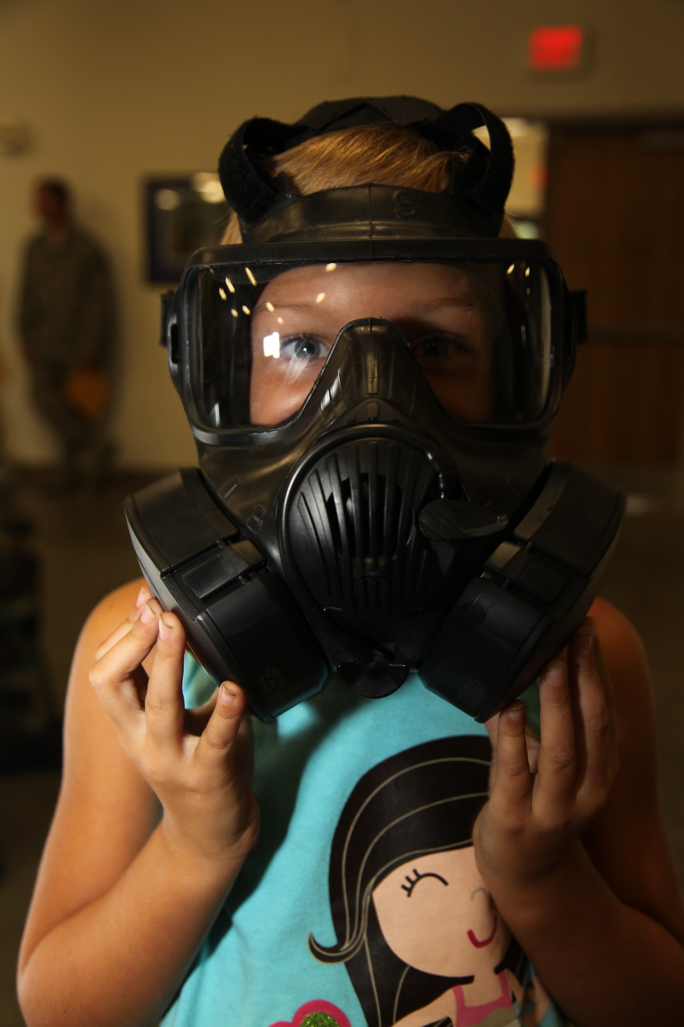 Cali Blodzinski, daughter of U.S. Air Force 1st Lt. Ann Blodzinski, 20th Fighter Wing Chief of Public Affairs, and U.S. Air Force Capt. Jason Blodzinski, 77th Fighter Squadron F-16 Fighting Falcon pilot,tries on a gas mask at the deployment processing center on Shaw Air Force Base, S.C. Sept. 19, 2012. Operation Take Flight gives children a chance to experience what processes their parents go through prior to deployments. (U.S. Air Force photo/1st Lt. Ann Blodzinski)(Released)

