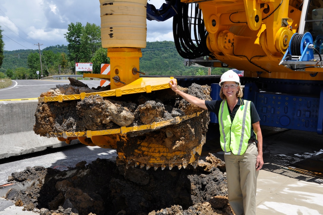 U.S. Army Corps of Engineers Nashville District project manager Linda Adcock stands by a Bauer Foundation Corporation drill rig July 11, 2012 that made the first excavation in the earthen portion of Center Hill Dam to install a concrete barrier wall which is the main feature of the Dam Seepage Rehabilitation project. (USACE photo by Fred Tucker)