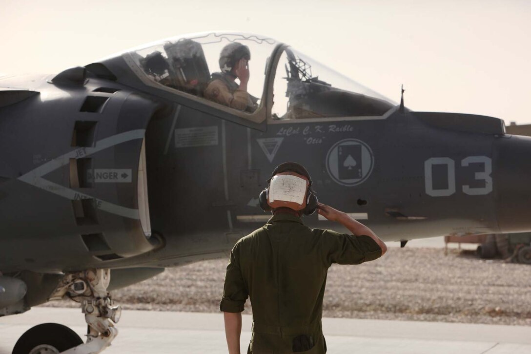 Lance Cpl. Harrison York, a AV-8B Harrier II Plus maintainer with Marine Attack Squadron 211, 3rd Marine Aircraft Wing (Forward), salutes Capt. Stephen White, a Harrier pilot, as he taxis in to the Camp Bastion, Afghanistan, flightline, Sept. 26. The aircraft bears the name of Lt. Col. Christopher Raible, the squadronâ€™s commanding officer who was killed during an attack on the Camp Bastion airfield, Sept. 14.