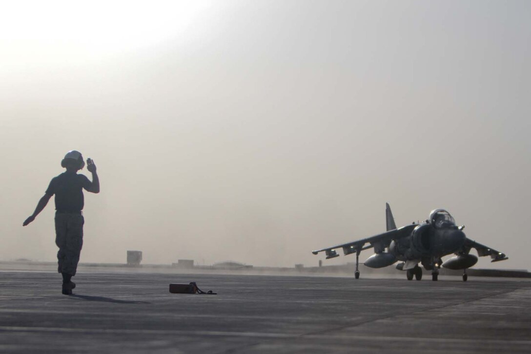 A Marine signals the pilot of an AV-8B Harrier II Plus with Marine Attack Squadron 211, 3rd Marine Aircraft Wing (Forward), into position on the tarmac, Sept. 18, 2012. The Harrierâ€™s equipped with a 25 mm Gatling gun and 500-pound bombs.