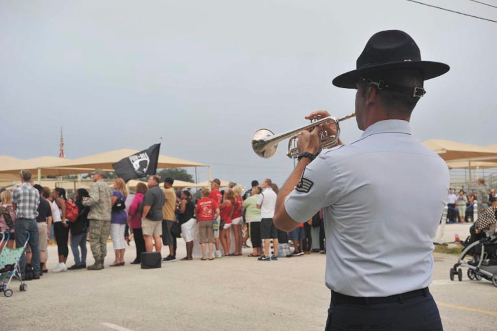 Staff Sgt. David Evans, 323rd Training Squadron trumpet apprentice, plays taps as active-duty service members, government civilians, and their family members stand in silence while the POW/MIA flag passes by Sept. 20 during the 37th Training Wing’s fourth annual POW/MIA 24-hour vigil run. (U.S. Air Force photo/Alan Boedeker)