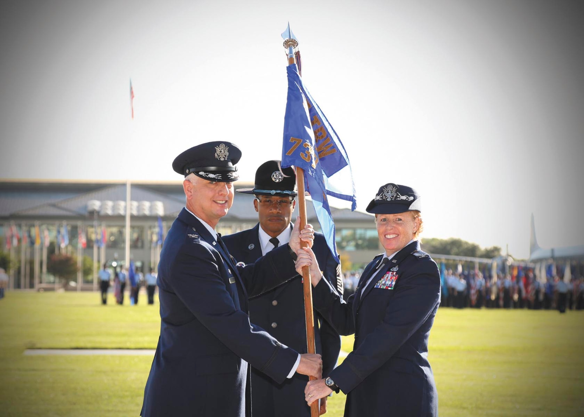 Col. Mark Camerer, 37th Training Wing commander, left, presents the 737th Training Group guidon to incoming commander Col. Deborah J. Liddick as Chief Master Sgt. Kenneth Williams, 737th TRG superintendent, looks on during the assumption of command ceremony Sept. 21 on the parade grounds at Joint Base San Antonio-Lackland, Texas. Liddick commands the Air Force’s only basic military training group. (U.S. Air Force photo/Robbin Cresswell)