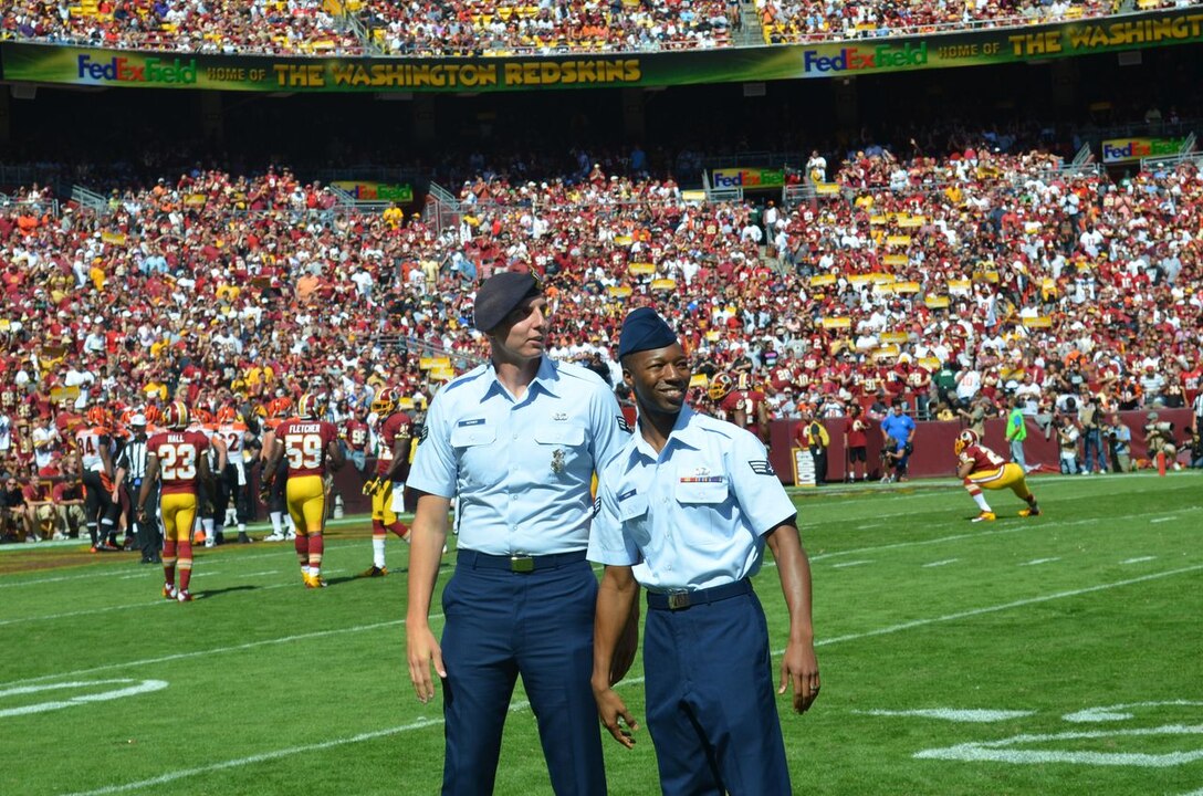 Senior Airman Matthew Werner, 811th Security Forces Squadron protective services team member; and Senior Airman Andrew Harris, 1st Helicopter Squadron aviation resource manager, wave to thousands of Washington Redskins fans at FedExField in Landover, Md., Sept 23.  The Airmen were the latest to be recognized in the Redskins and USAA Military Appreciation Series, in which the Airmen starred in several 30-second vignettes shown at the game as well as aired on WRC-TV 4's "Inside the Redskins" and Comcast Sports Net's  "Redskins Nation"  programs.  (Courtesy photo/Washington Redskins)