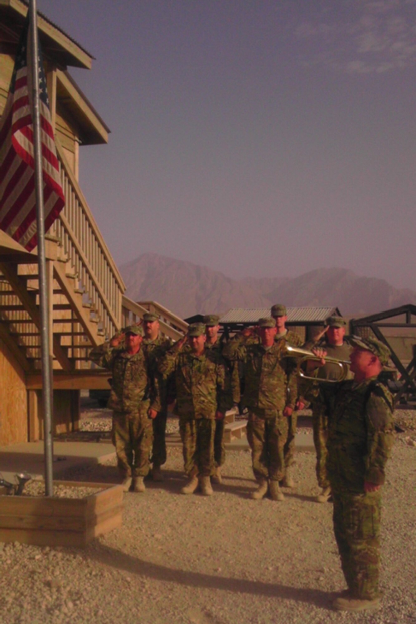 CAMP MARMAL, Afghanistan – With the mountains of northern Afghanistan in the distance, Lt. Col. Rich Gaddis sounds Taps at a Forward Operating Base memorial ceremony on September 11, 2012.  In formation in the front row from left to right are, Staff Sgt. McMillan, Chief Warrant Officer 4 Grover, Master Sgt. Wollett, Chief Warrant Officer 3 Carter; and in the back row are, Chief Warrant Officer 2 Buckalew, Chief Warrant Officer 3 Jones, and Chief Warrant Officer 2 Landies.  (U.S. Air Force photo by Tech. Sgt. Tamieka Wanzo)