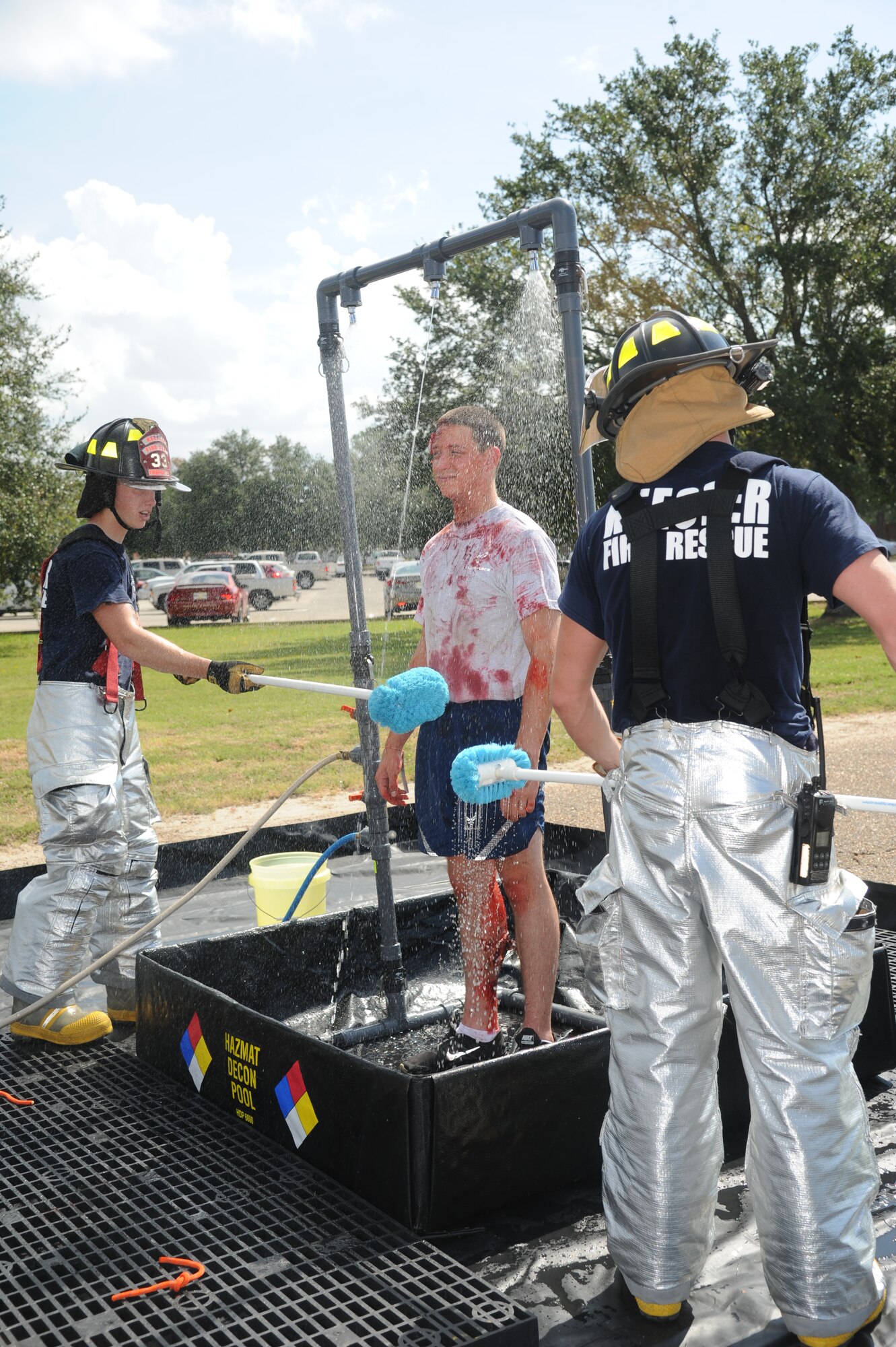Airmen 1st Class Kyle Ledford and Seth Corn, Keesler firefighters, decontaminate Airman Basic Cody Martin, 336th Training Squadron, during a hazardous material exercise Sept. 27, 2012, at Keesler Air Force Base, Miss.  In the scenario, a routine delivery flatbed trailer transporting hazardous material is struck by a van transporting Airmen causing one of the containers to fall from the vehicle and rupture. The exercise helped prepare first responders in the event of a real-world incident.  (U.S. Air Force photo by Kemberly Groue)