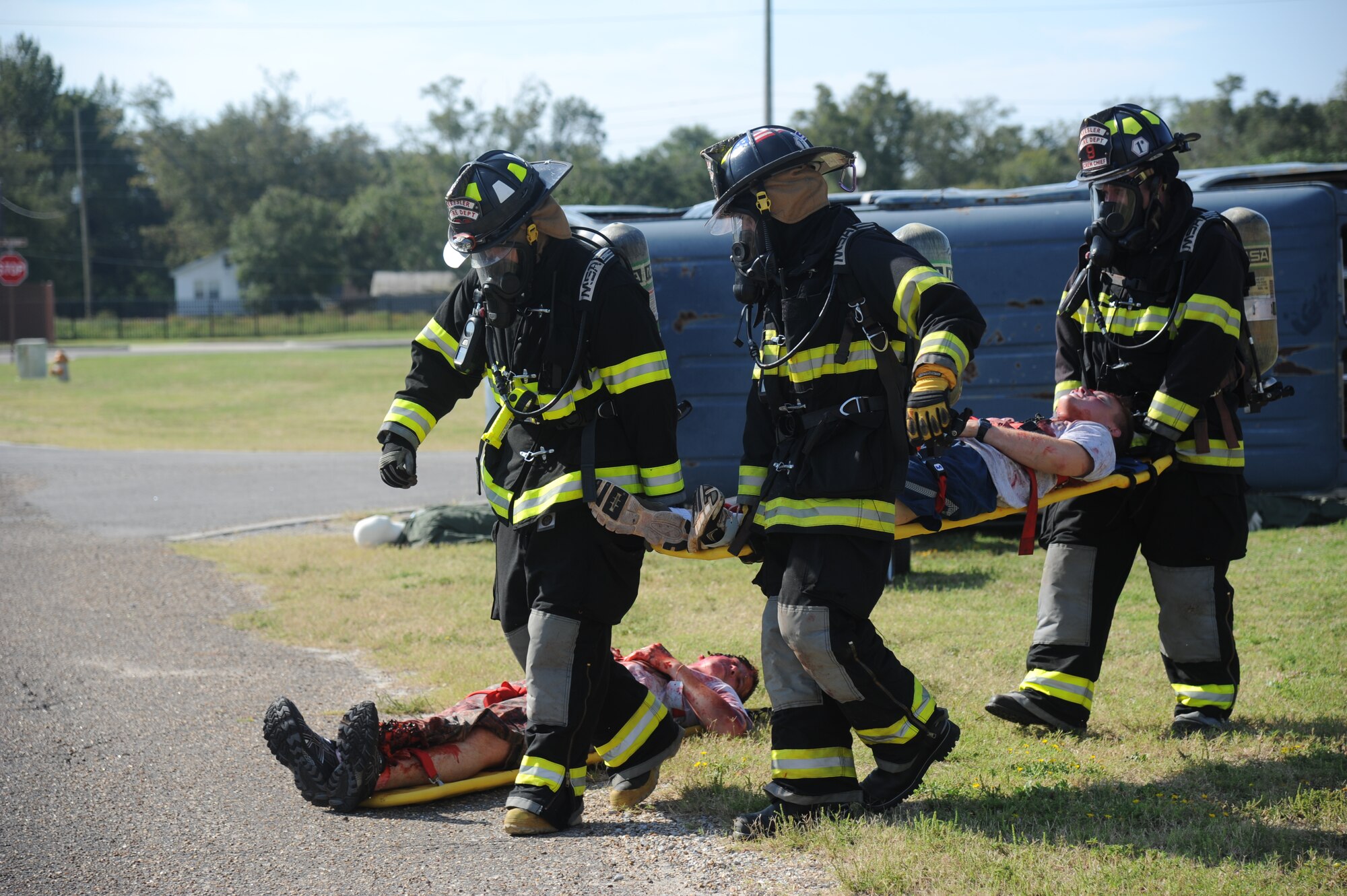 Staff Sgt. Nicholas Fasola, Dave Cleland and Donovan Oosterhuis, Keesler firefighters, move a “victim” away from the "accident" site during a hazardous material exercise Sept. 27, 2012, at Keesler Air Force Base, Miss.  In the scenario a routine delivery flatbed trailer transporting hazardous material is struck by a van transporting Airmen causing one of the containers to fall from the vehicle and rupture. The exercise helped prepare first responders in the event of a real-world incident.  (U.S. Air Force photo by Kemberly Groue)