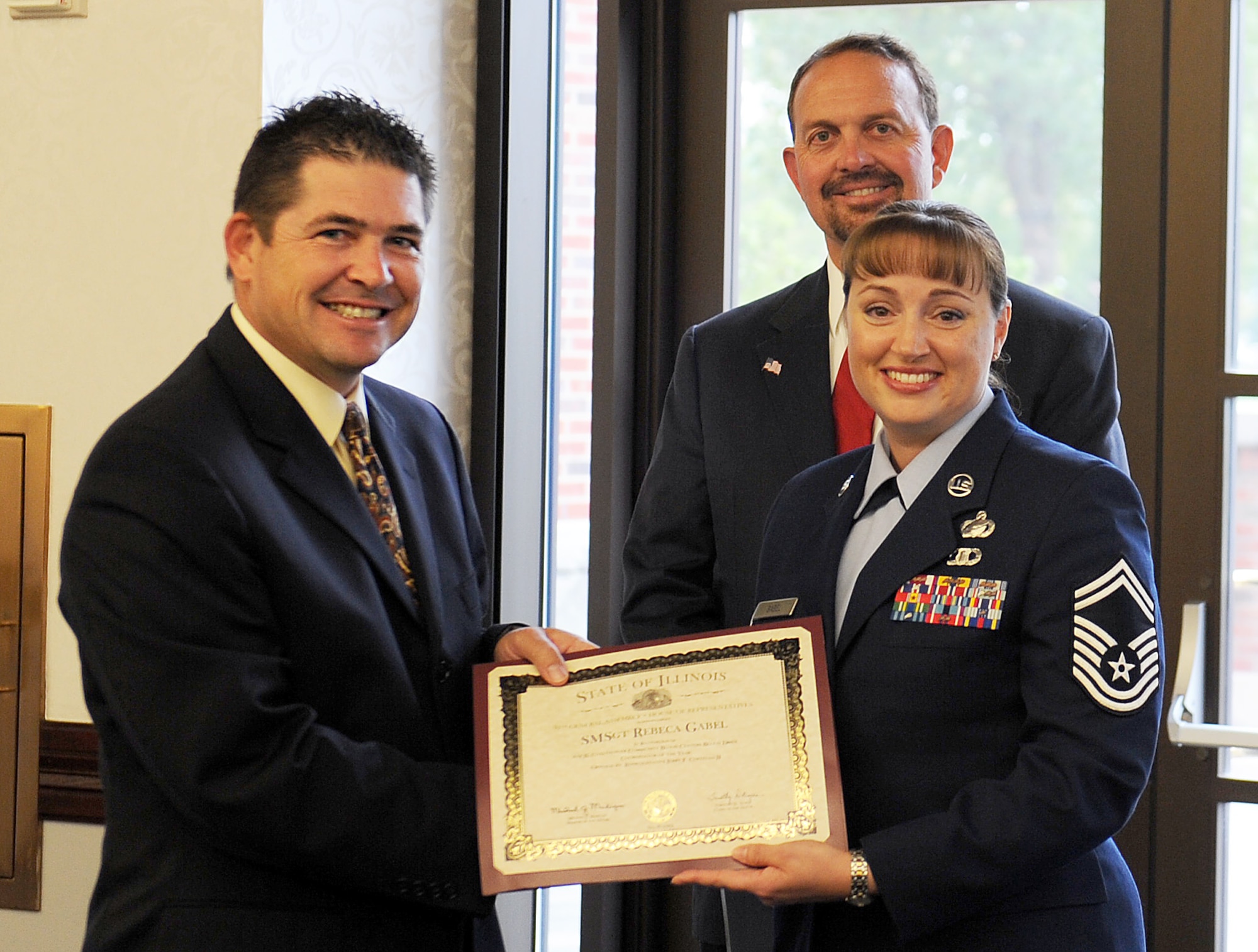 Illinois Senator Kyle McCarter presents Senior Master Sgt. Rebeca Gabel, Headquarters Air Mobility Command Military Personnel Programs manager, the Illinois Innovative Blood Drive Coordinator award Sept. 27, 2012, at Scott Air Force Base, Ill. Illinois State Representative Paul J. Evans was also in attendance to present the award. Gabel, who also serves as the Mississippi Valley Regional Blood Center coordinator for Scott AFB, facilitated 16 blood drives collecting more than 500 units of blood and affecting more than 1,500 lives in the surrounding community. (U.S. Air Force photo/Airman 1st Class Jaeda Waffer)